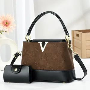 Detail der gesteppten braunen Wildledertasche mit Goldlogo und passender kleiner Geldbörse