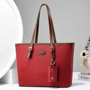 Detail of red lychee grain leather tote bag with adjustable brown strap and gold hardware