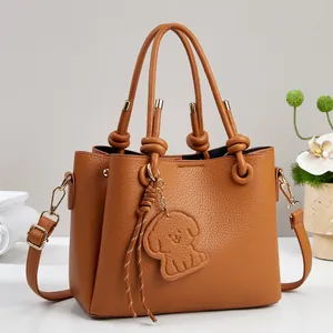 Elegant brown pebble leather handbag with knot handles and cute dog charm ornament