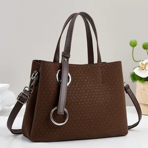 Detail of dark brown tote bag with woven texture and large silver metal buckle ornament