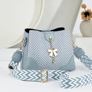 Blue and white herringbone bucket bag with leather trim and decorative chain pendant