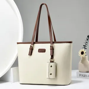 Chic cream tote bag with dark brown handles and a matching mini pouch charm