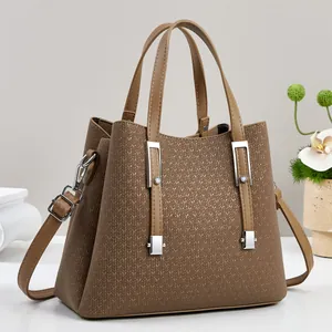 Detail of brown textured leather tote bag featuring silver hardware and crossbody strap