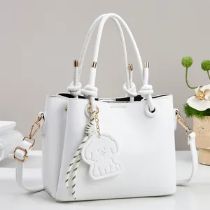 Detail of white litchi pattern leather handbag with knotted handles and dog charm