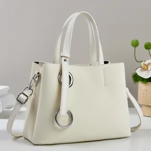 Detail of cream white tote bag featuring woven texture and silver metal rings