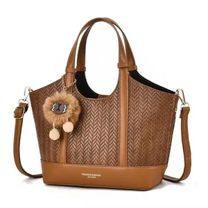 Brown leather tote bag with V-shaped woven texture and plush ball charm in a minimalist style