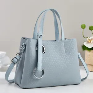 Detail of light blue tote bag with V-shaped embossing and silver metal ring decoration