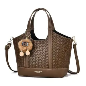 Detail of woven leather pattern and plush charm on brown dual-handle bucket bag