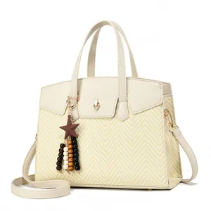 Detail showing elegant beige leather and woven straw texture with a star charm