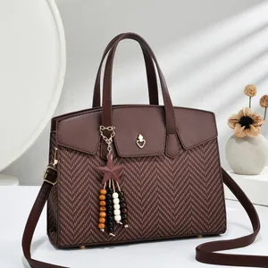Brown herringbone crossbody handbag with gold heart detail and wooden bead tassel