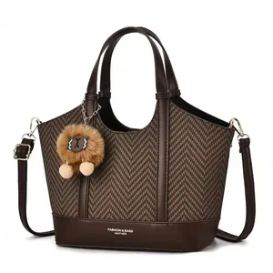 Detail of herringbone fabric tote bag with faux leather trim and plush pompom charm
