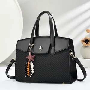 Detail of black crossbody bag featuring heart lock, star charm, and woven texture