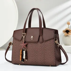 Detail of brown herringbone fabric handbag with star charm and heart gold buckle