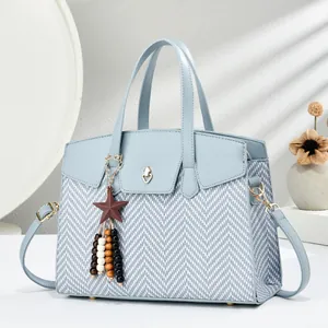 Detail of light blue crossbody bag with herringbone weave, gold lock, and star pendant