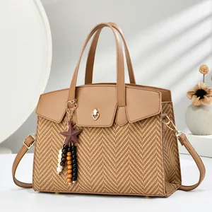 Detail of khaki leather bag with woven panels and a gold heart lock and star pendant