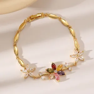 Makro-Detail des vergoldeten Blattarmbandes mit bunten Zirkonia-Steinen und Blumendesign