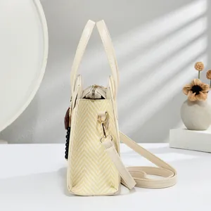 Detail of beige tote bag with straw texture side panels and star-shaped charm