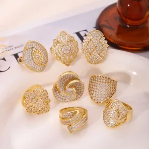 Set of 8 gold plated geometric rings with white stones displayed on a ceramic tray