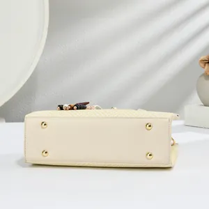Detailed view of beige tote bag bottom with four gold metal feet and premium leather stitching