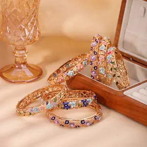 Elegant hollow floral enamel bracelets with colorful gemstones on a warm silk background