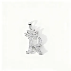 Close-up detail of silver zircon encrusted letter R crown pendant, sparkling stone texture.