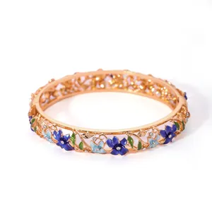 Close-up of hollow gold-plated cloisonne bracelet with blue enamel floral details