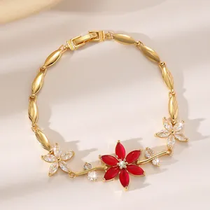 Makroaufnahme: Vergoldetes Blattarmband mit roten Zirkonia-Blüten und Schmuckschließe