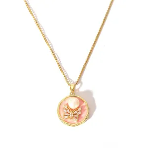 Détail d'un collier doré avec pendentif papillon en émail rose et perle blanche