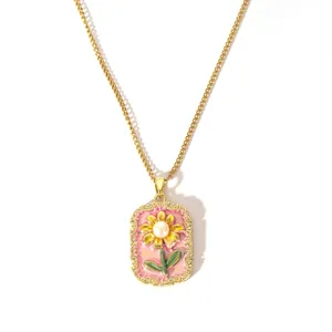 Détail du pendentif floral en émail avec perle sur une fine chaîne dorée