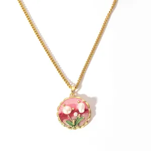 Détail du pendentif fleur dorée avec émail rose et perles incrustées sur chaîne fine