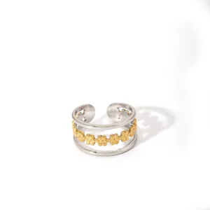 Macro view of gold flower pattern layered between two silver rings in two-tone design