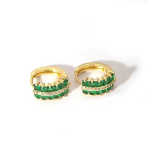 Detailed view of 18K gold huggie earrings with emerald-green crystals and zircon accents