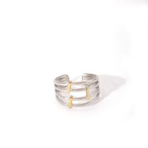 Detail of silver multi-layer open ring with three vertical gold metal accents