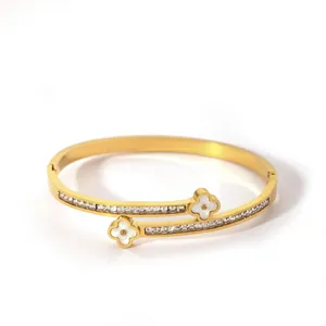 Detail of gold-plated bangle with two white clover charms and paved zircon stones