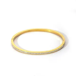 Detailed view of gold plated bangle with inlaid white cubic zirconia and side clasp
