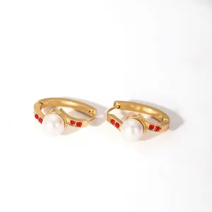 Detail of 18K gold hoop earrings with central pearl and red zircon accents