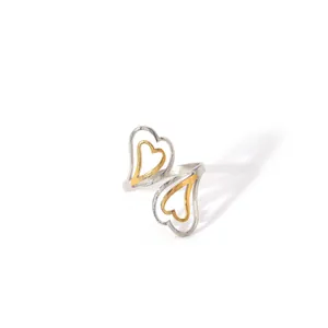 Detail of bypass ring with interlocking gold and silver hearts in polished steel