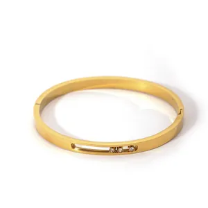 Detail view of gold-plated bangle with three sliding white zircons in a central slot