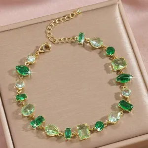Macro detail of various green crystal shapes and gold link chain in a luxury box