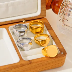 Five minimalist titanium steel signet rings set in gold and silver within a wood jewelry box