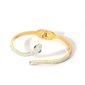 Detailed close-up of golden snake bracelet with micro-paved white zircons and green gem eyes