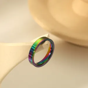Polished 4mm rainbow stainless steel ring displayed on a white geometric stand