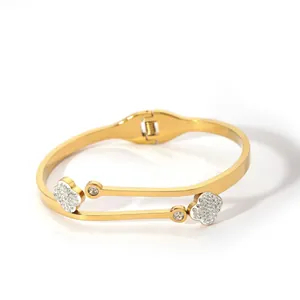 Detail view of gold clover bangle with cubic zirconia accents and hinge closure mechanism