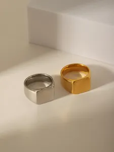 Detail of square signet rings in gold and silver finish on minimalist stone blocks
