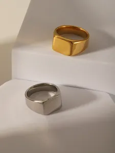Polished gold and silver stainless steel signet rings on a modern geometric display