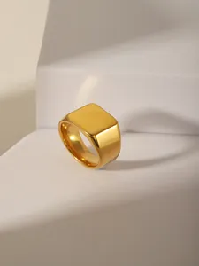 Close-up of minimalist square gold signet ring with mirror finish on geometric stand