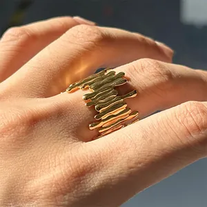 Macro detail of irregular liquid lava texture on gold plated wide band stainless steel ring