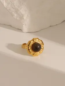 Detailed close-up of retro gold ring with brown gemstone and sunburst texture