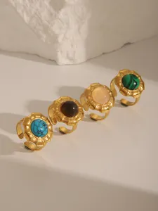 Detail of four gold adjustable rings with blue, brown, pink, and green natural stones