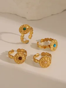 Detail of four vintage gold rings with colorful natural stone inlays and sun patterns